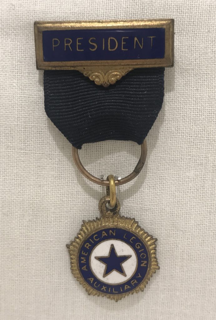 Small medal with pendant and blue ribbon signifying wearer was the president of the American Legion Auxiliary