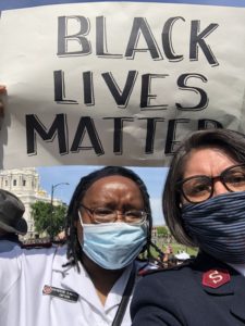 Major Katherine Clausell and another female Salvation Army officer wear face masks during a peaceful demonstration in Washington D.C. in 2020. Clausell holds a sign above her head that reads "Black Lives Matter."