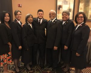 Color photograph of the Santos Family all wearing their Salvation Army uniforms. The family consists of two parents and four adult children