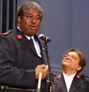 Photograph showing Majors Stephen and Diane Harper speaking at a microphone