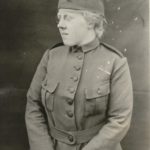 Black and white photograph of a woman wearing a cloth WWI overseas cap and military styled uniform.