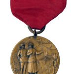 Photo of a pin on brass medal with red ribbon. The medal is circular and features a male and female Salvation Army War Service workers in front of a hut.