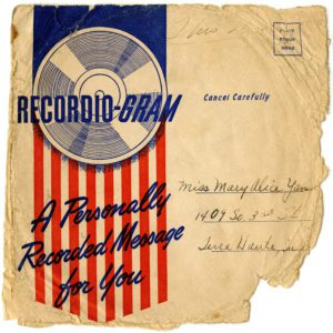 Digital scan of a square beige colored paper envelope. On the front, left side is a graphic in red and blue. The top of the graphic shows a record with blue background and "recordio-gram" text printed over record image. Bottom of graphic is a series of red verticle stripes and text in blue script that reads "A Personally Recorded Message for You." The right side of the envelope bears standard postal addressing and stamp information. Envelope was addressed to Miss Mary Alice Yanse from Terrre Haute, IN