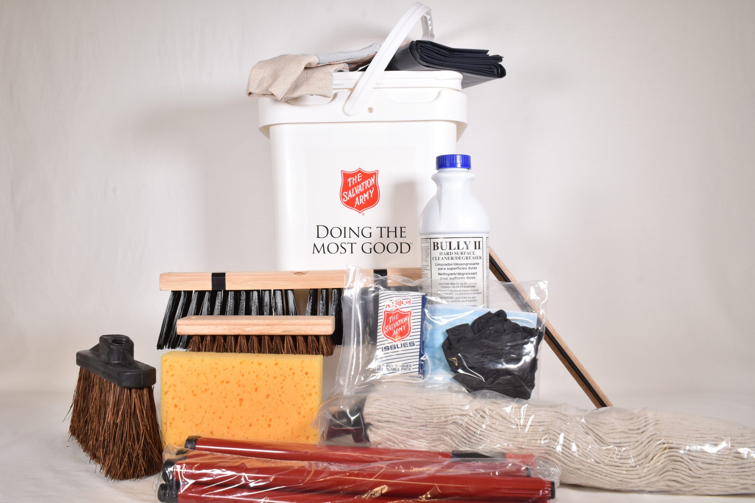 A white plastic rectangular 40 gallon pail with Salvation Army Red Shield logo and brand promise "Doing The Most Good." Arranged around the pail are several cleaning supplies including a disassembled mop, sponges, gloves, and bleach.