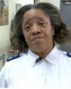 A middle aged African American woman with shoulder length center parted hair wearing a white button down shirt with blue Soldier epaulets.