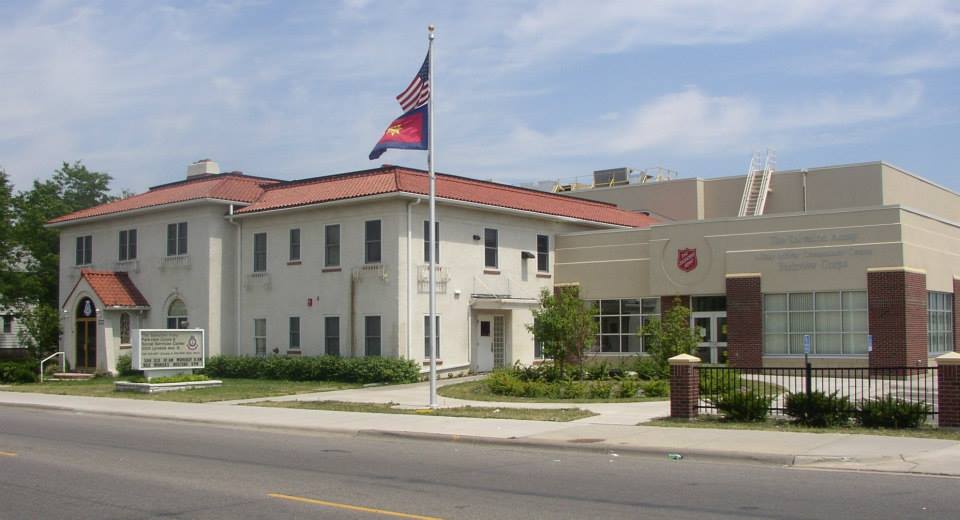 Photograph of a large white two story building with terracotta roof. It has a more modern addition. A flagpole is in front of the addition with US and Salvation Army flags flying.