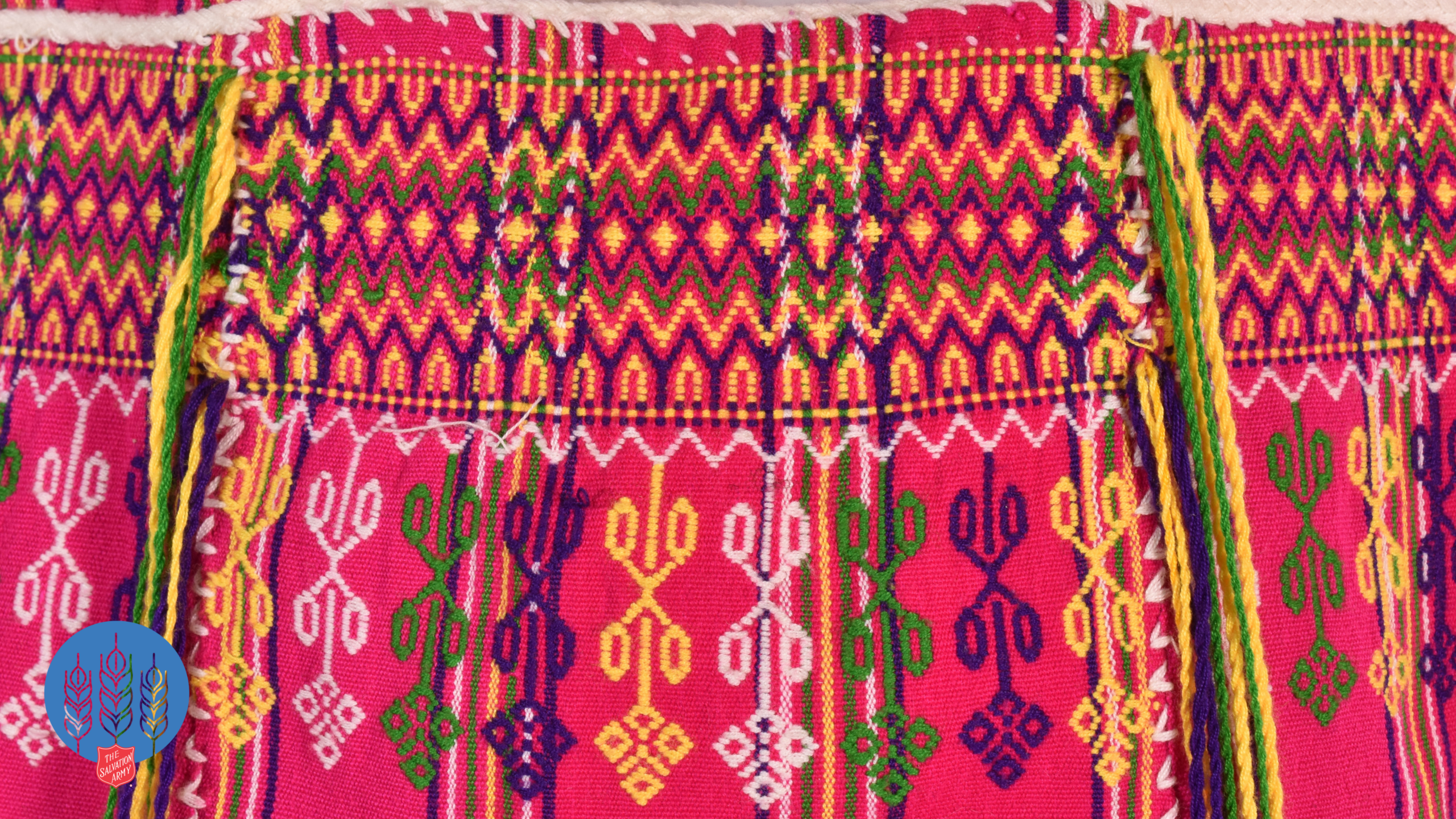 Detail photograph of colorful embroidery on a pink shoulder bag.