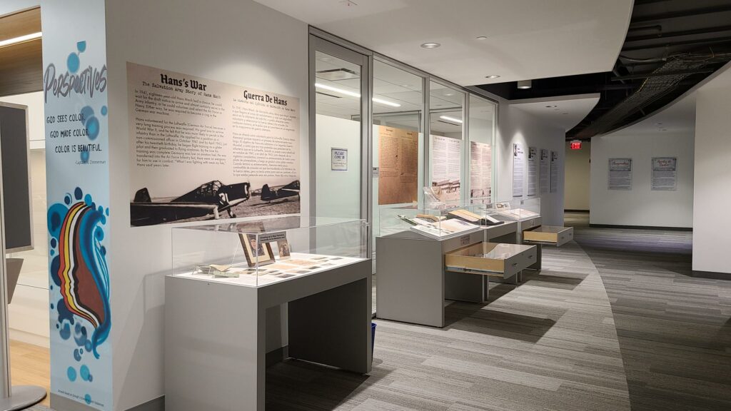 Color photograph showing a hallway with four exhibit cases positioned against a wall