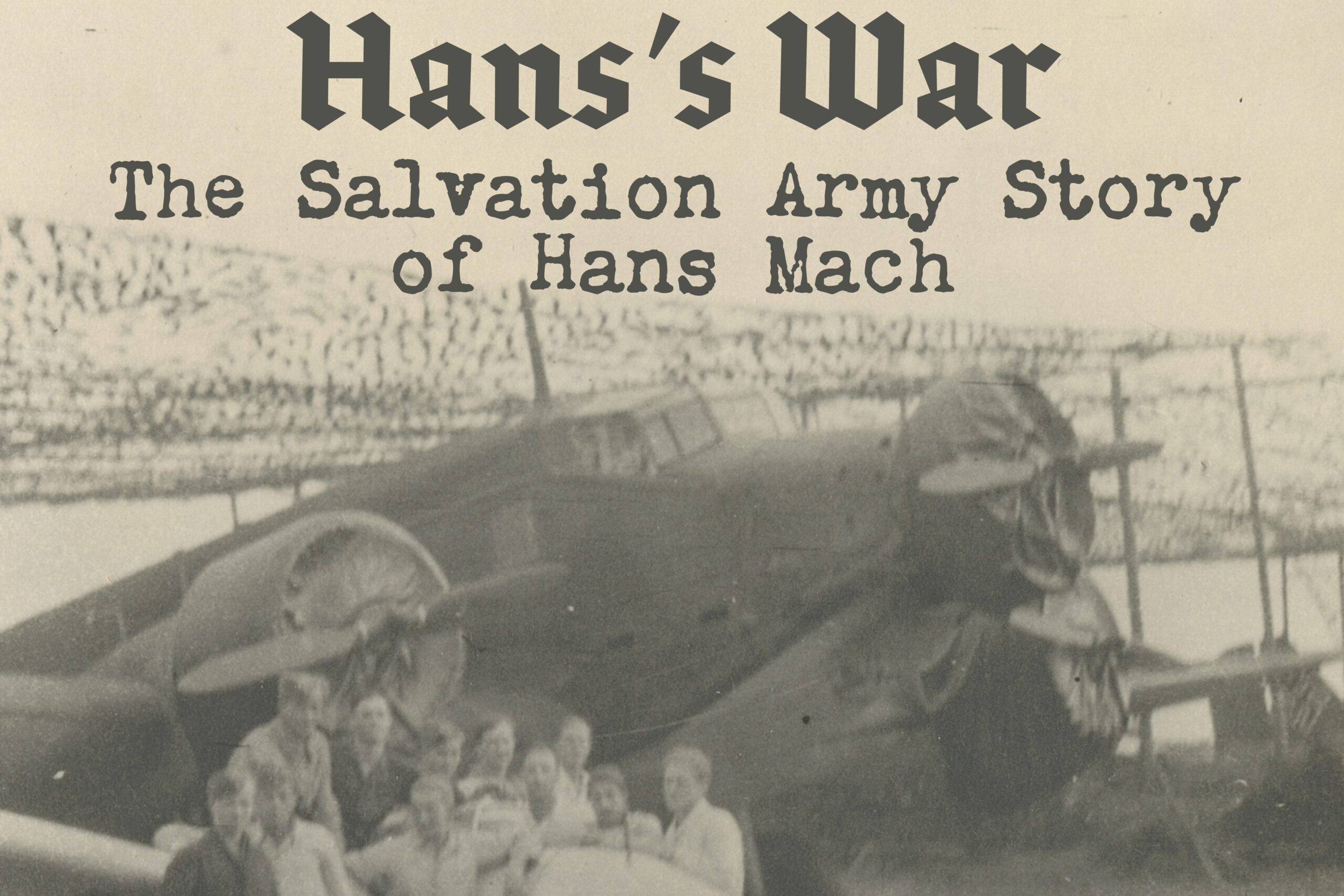 Black and white photographic label showing soldiers posing with a 1940s airplane. Text reads: "Hans's War: The Salvation Army Story of Hans Mach"