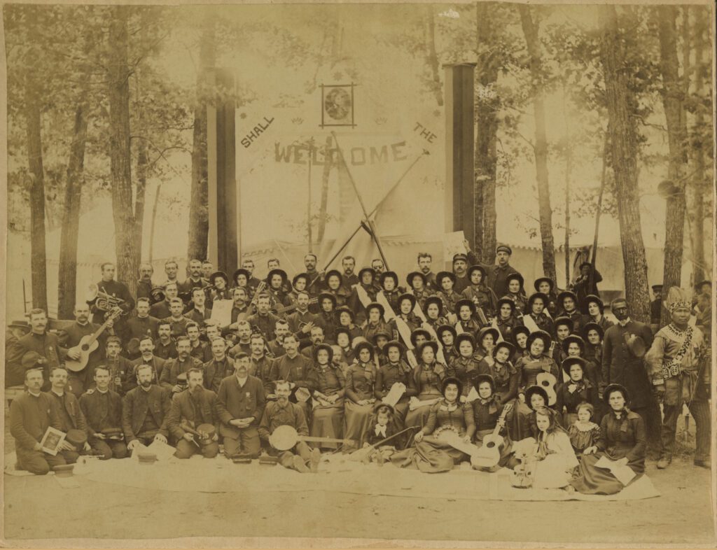 A nineteenth century photo of a large group of people posing in the woods.