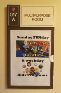 Wall sign reading "Sunday FUNday Arts & Crafts & weekday Kids Programs.